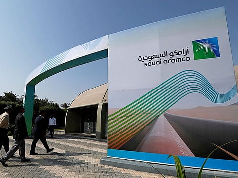 The logo of Aramco is seen as security personnel walk before the start of a press conference by Aramco at the Plaza Conference Center in Dhahran, Saudi Arabia