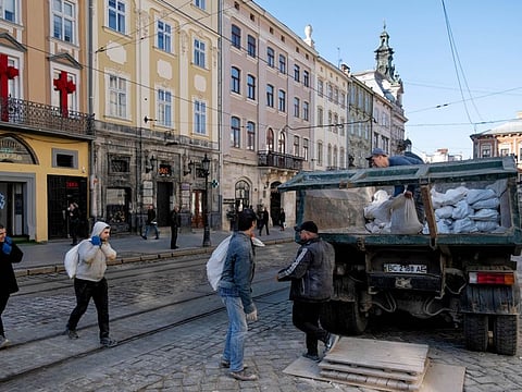 Construction workers load sacks of waste onto a truck in the old town of Lviv, Ukraine, on Friday, March 25, 2022.
