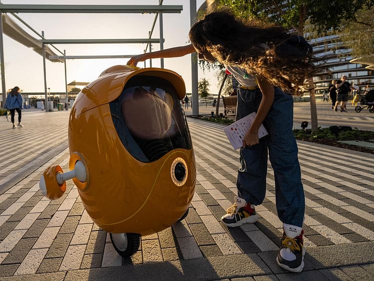 A visitor interacts with Opti the robot at the Mobility District_Large Image_m47879-1648288473646