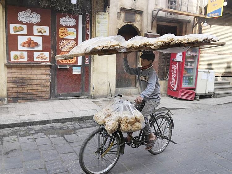 A vendor balances a tray of Egyptian traditional "Baladi" flatbread 
