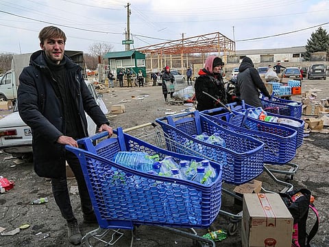 Local residents carry water from the food warehouse, on the territory which is under the Government of the Donetsk People's Republic control, on the outskirts of Mariupol, Ukraine,