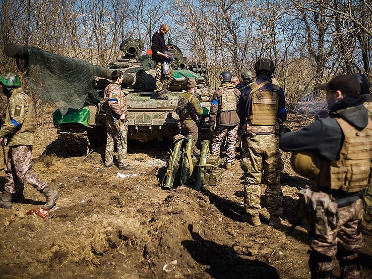 Ukrainian soldiers get organised to pose for pictures next to a captured Russian tank.  