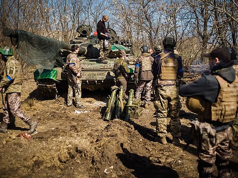 Ukrainian soldiers get organised to pose for pictures next to a captured Russian tank.  