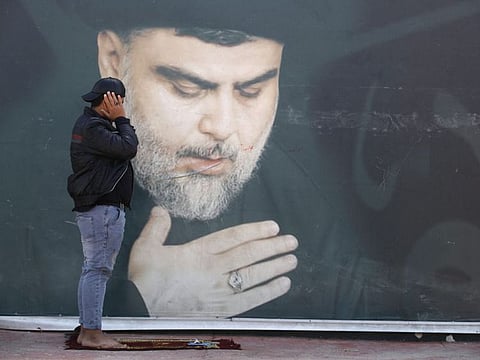 A supporter of Iraqi Shiite cleric Moqtada Al Sadr, depicted on the background billboard, performs Friday prayers in Sadr City, east of the capital Baghdad, on March 25, 2022. 