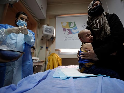 A woman holds her crying child at the cancer ward of the Children's Hospital in Damascus.