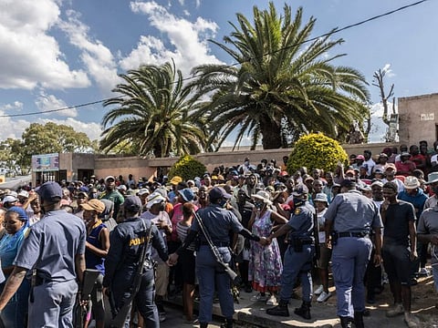 South African Police Service officers prevent residents from blocking a street as they protest against the rise of crime in the area in Diepsloot, South Africa, on April 6, 2022. 