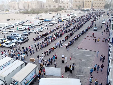 An aerial view shows people line up to receive iftar meals, donated by a charity, in Mahboula, south of Kuwait City on April 10, 2022.  