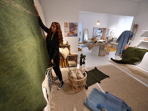 A shopkeeper arranges rugs woven by women in the southwestern Tunisian oasis of Nefta, at a shop run by Shanti, a social enterprise that helps artisans from across the North African country, in the capital Tunis, on April 15, 2022. 