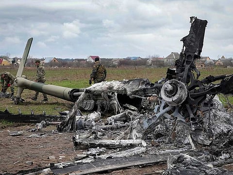 Ukrainian sappers search for unexploded explosives at the burnt remains of a Russian helicopter destroyed during recent fighting between Russian and Ukrainian forces at the Antonov airport in Hostomel, outskirts of Kyiv, Ukraine, Monday, April 18, 2022. 