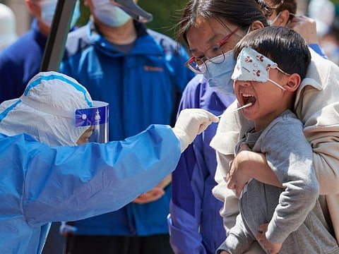 A child receives a swab test for the Covid-19 coronavirus in a compound during a Covid-19 lockdown in Pudong district in Shanghai on April 17, 2022.