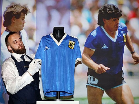 A Sotheby's technician adjusts a football shirt worn by Argentina's Diego Maradona during the 1986 World Cup quarter-final match against England, during a photocall at Sotheby's auction house in London on April 20, 2022, ahead of its sale.