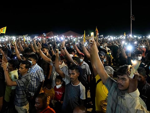 Sri Lankans during a vigil condemning police shooting at protesters outside the president's office in Colombo on April 19, 2022.  