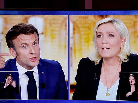 A picture shows a TV screen displaying a live televised between French President and La Republique en Marche (LREM) party candidate for re-election Emmanuel Macron (L) and French far-right party Rassemblement National (RN) presidential candidate Marine Le Pen (R), broadcasted on French TV channels TF1 and France 2, in Saint-Denis, north of Paris, ahead of the second round of France's presidential election. 