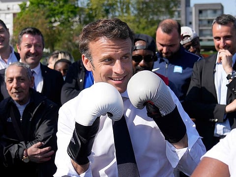 French President and La Republique en Marche (LREM) party candidate for re-election Emmanuel Macron wears boxing gloves as he meets a local boxer at the Auguste Delaune stadium on April 21, 2022 during a campaign visit in Saint-Denis, outside Paris.