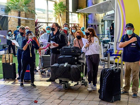 In this file photo taken on November 1, 2021 an airport employee assists passengers through the arrival area at Phuket International Airport as Thailand welcomes the first group of tourists fully vaccinated against the Covid-19 coronavirus without quarantine in Phuket.