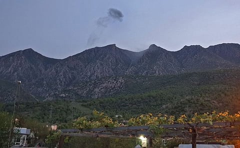 A picture taken on April 19, 2022, shows smoke billowing from behind the mountains of Matin (Jabal Matin) in the town of Chiladze following a Turkish offensive targeting rebels in the north's autonomous Kurdistan region.  