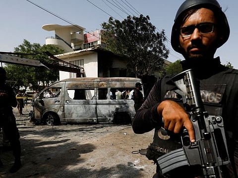 Police officers stand guard near a passenger van, after a blast at the entrance of the Confucius Institute University of Karachi, Pakistan April 26, 2022. 