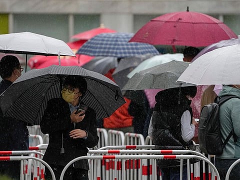 Residents line up in the rain for COVID test at a commercial office complex on April 27, 2022, in Beijing. 