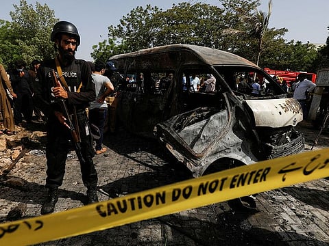 A police officer stands guard near a passenger van, cordoned after a blast at the entrance of the Confucius Institute University of Karachi, Pakistan, April 26, 2022. 