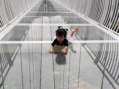 A young visitor crawls on the Bach Long glass bridge in Moc Chau district in Vietnam's Son La province on April 29, 2022.