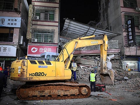 Rescuers work next to an excavator at a site where a building collapsed in Changsha, Hunan province, China. 