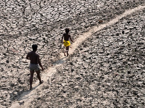 A man and a boy walk across an almost dried up bed of river Yamuna following hot weather in New Delhi, India, Monday, May 2, 2022.