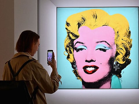 In this file photo taken on April 29, 2022 a woman takes a photo of Andy Warhol's 'Shot Sage Blue Marilyn' during Christie's 20th and 21st Century Art press preview at Christie's New York in New York City.
