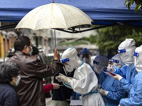 A team of health workers and volunteers in personal protective equipment (PPE) check the identification of residents at a Covid-19 testing station at a neighbourhood where a suspected flare up in cases occurred in Shanghai, China.