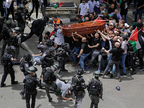 Israeli police confront with mourners as they carry the casket of slain Al Jazeera veteran journalist Shireen Abu Aqleh during her funeral in east Jerusalem, on May 13, 2022.  