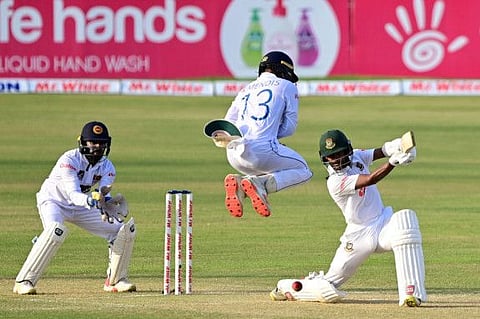 Bangladesh's Mahmudul Hasan Joy (right) plays a shot as Sri Lanka's Kusal Mendis jumps next to wicketkeeper Niroshan Dickwella (left) during the second day of the first Test at the Zahur Ahmed Chowdhury Stadium in Chittagong.