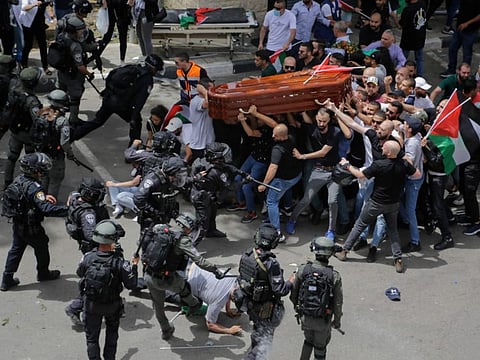 Israeli police assault mourners as they carry the casket of slain Al Jazeera veteran journalist Shireen Abu Akleh during her funeral in east Jerusalem, May 13, 2022. 