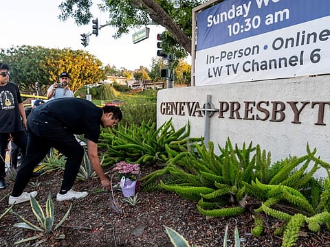 Hector Gomez, left, and Jordi Poblete, worship leaders at the Mariners Church Irvine leave flowers outside the Geneva Presbyterian Church in Laguna Woods, Calif., Sunday, May 15, 2022, after a fatal shooting.