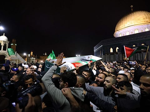 Palestinian mourners carry the body of Walid Al Sharif, 23, who died of wounds suffered last month during clashes with Israeli police at Jerusalem's flashpoint Al Aqsa mosque compound, on May 16, 2022 in front of the Dome of the Rock mosque at the Al Aqsa compound.