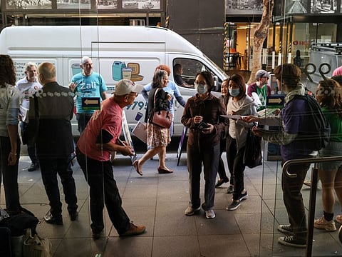 Campaign volunteers address voters at the entrance to an Australian Electoral Commission early voting centre ahead of the national election, in the Central Business District of Sydney, Australia, May 17, 2022. 