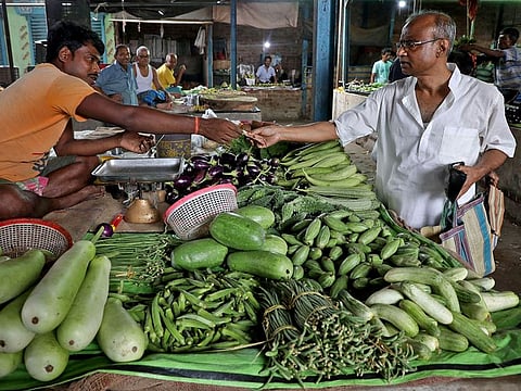 Nikhil Kumar Mondal, 65, a retired school headmaster, buys vegetables from a vendor at a market on the outskirts of Kolkata, India.