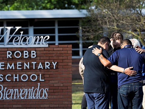 People gather at Robb Elementary School , the scene of a mass shooting in Uvalde, Texas.