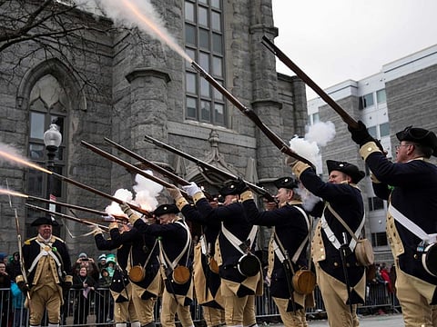 In this file photo taken on March 19, 2017 American Revolutionary War reenactors fire musket blanks during the annual St. Patrick's Day parade in South Boston, Massachusetts. 