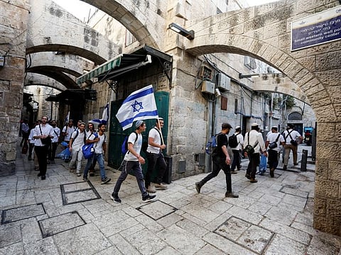 Jewish men carry Israeli national flags as they walk in an alley, inside Jerusalem's Old city May 29, 2022. 