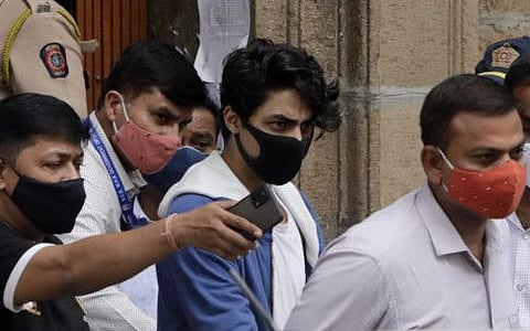 Bollywood megastar Shah Rukh Khan's son Aryan Khan, center, is escorted by law enforcement officials from the Narcotics Control Bureau office for a medical check in Mumbai, India, Friday, Oct. 8, 2021. Khan was on Friday, May 27, cleared by authorities in a drugs-on-cruise case with no possession and corroborative evidence suggesting his involvement in a drug network, the investigating agency said.