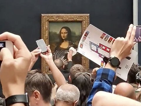 A security guard cleans the smeared cream from the glass protecting the Mona Lisa at the Louvre Museum, in Paris, France, Monday, May 30, 2022.