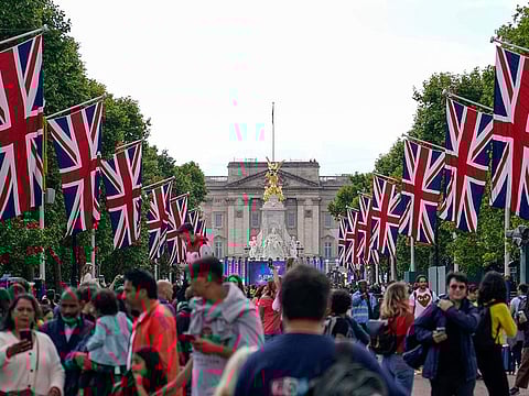 People walk along The Mall in London, on June 1, 2022 as they camp out ahead of the start of the Queen's Jubilee weekend. Britain will celebrate Queen Elizabeth II’s 70 years on the throne with four days of festivities beginning with her ceremonial birthday parade on June 2, 2022.  
