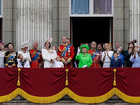 Britain's Queen Elizabeth II waves as she watches the flypast, with Prince Philip, to right, Prince William, centre, with his son Prince George, front, Kate, Duchess of Cambridge holding Princess Charlotte, centre left, with The Prince of Wales standing with The Duchess of Cornwall, and Princess Anne, fourth left, on the balcony during the Trooping The Colour parade at Buckingham Palace, in London, on June 11, 2016.  