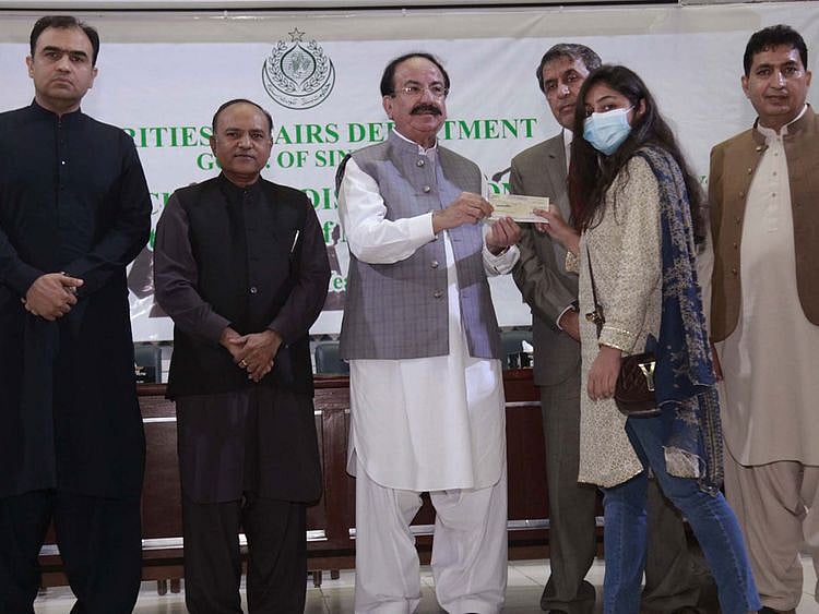 Sindh Minister for Minorities, Giyan Chand Essarani, gives a scholarship cheque to a female student from a minorty community..