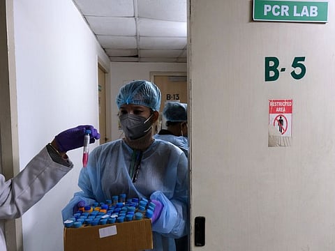 A technician inspects samples for RT PCR testing in Noida, Uttar Pradesh, on January 7, 2022.  