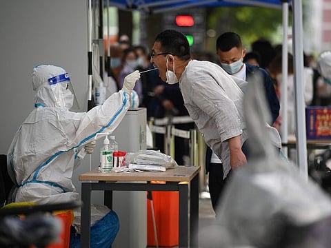 A health worker takes a swab sample from a man to be tested for the Covid-19 coronavirus at a swab collection site in Beijing on June 13, 2022.