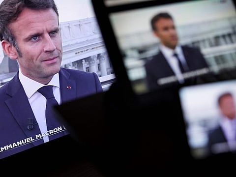 A picture taken in Paris on June 16, 2022, shows TV screens displaying a live televised interview by a French television channel of French President Emmanuel Macron, during his official visit to the Ukraine.