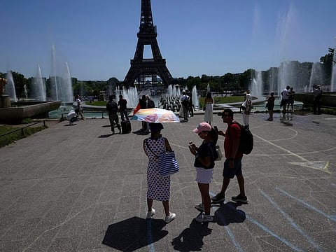 A tourist uses an umbrella to seek shade from the sun at the Trocadero fountains, Friday, June 17, 2022 in Paris.