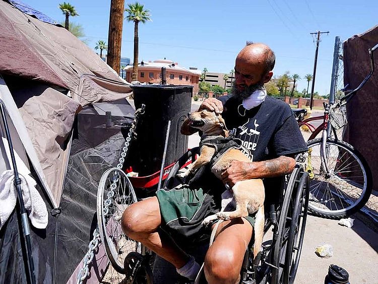 A man pets his dog at their tent 