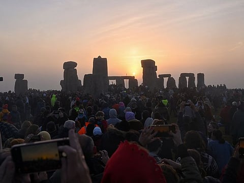 Revellers celebrate the Summer Solstice as the sun rises at Stonehenge, near Amesbury, in Wiltshire, southern England on June 21, 2022, in a festival, which dates back thousands of years, celebrating the longest day of the year when the sun is at its maximum elevation. The stone monument -- carved and constructed at a time when there were no metal tools -- symbolises Britain's semi-mythical pre-historic period, and has spawned countless legends. 