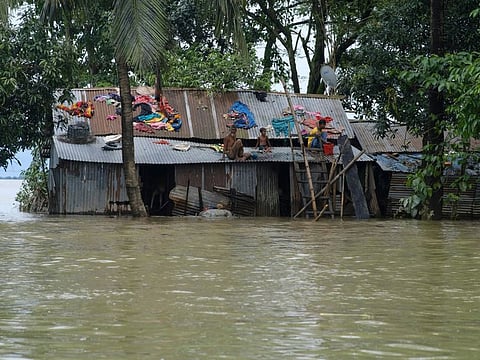 People sit on the tin roofs of their houses surrounded by flood waters in Sylhet, Bangladesh, on  June 21, 2022. Villagers in northeastern Bangladesh are crowding makeshift refugee centres and scrambling to meet boats arriving with food and fresh water as massive floods, which have killed dozens of people and displaced hundreds of thousands. 